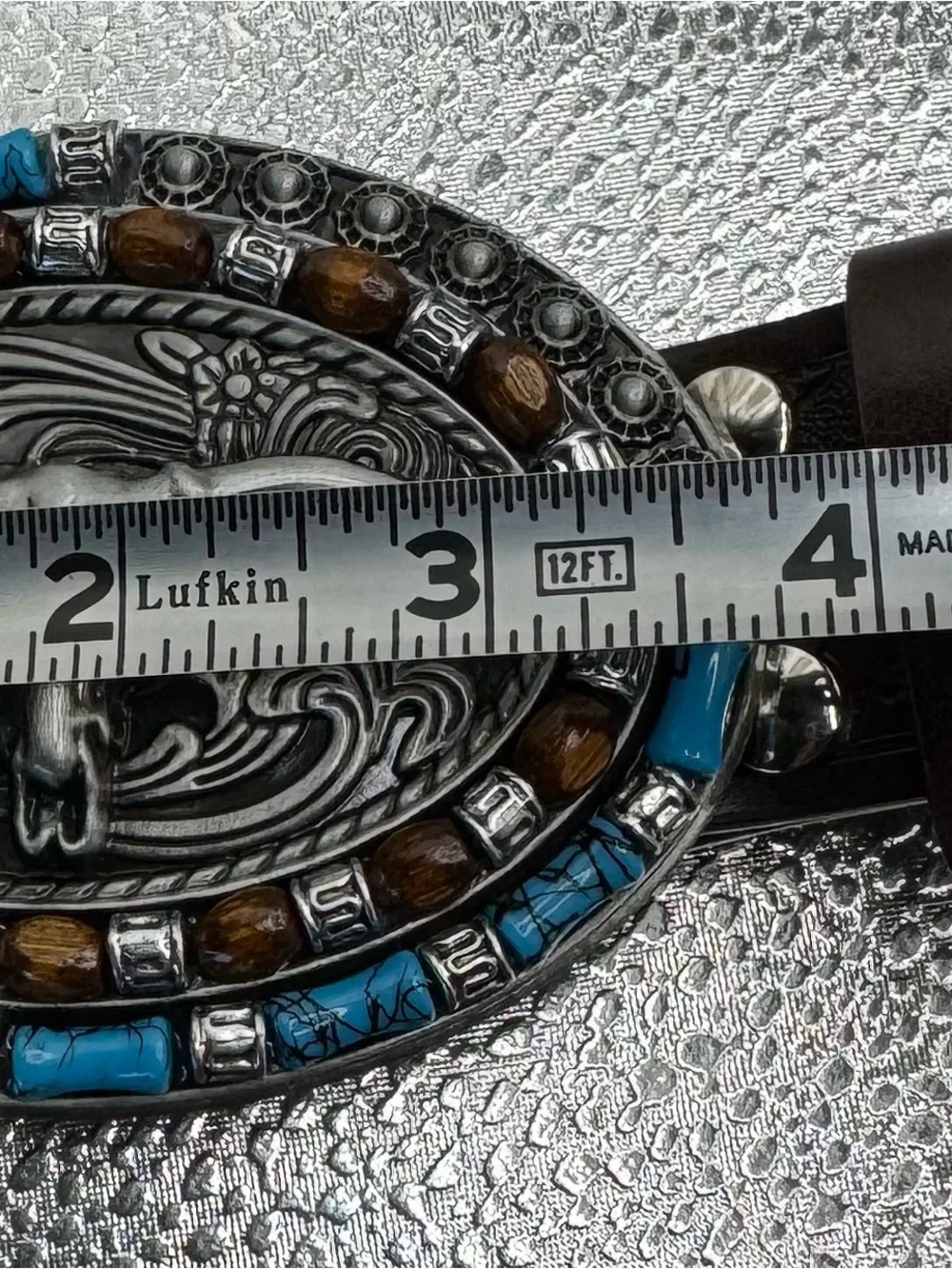 style longhorn skull belt buckle paired with a brown embossed leather strap.